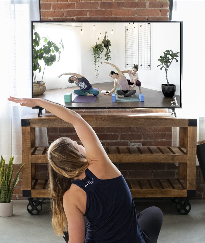 Woman practicing yoga with The Yoga Abbey on screen